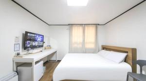 a bedroom with a bed and a desk and a tv at The Oakra Hotel in Jeju