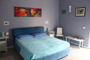 a bedroom with a blue bed with a painting on the wall at Esedra B&B in Palermo
