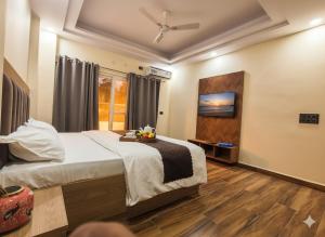 Un dormitorio con una cama y un televisor en la pared. en Expo Residency Inn, en Jāmb