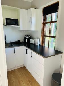 een keuken met witte kasten en een zwart aanrechtblad bij Modern Rustic Backyard Studio Private & Cosy Retreat in Mount Tamborine
