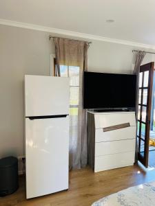 een woonkamer met een tv en een witte koelkast bij Modern Rustic Backyard Studio Private & Cosy Retreat in Mount Tamborine
