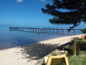 a beach with benches and a pier in the water at Linareva Moorea Beach Resort in Haapiti