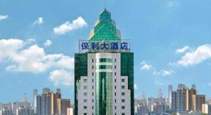 a tall green and white building with a sign on it at Hubei Poly Hotel in Wuhan