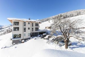 a building in the snow with cars parked at Eberharthof in Saalbach-Hinterglemm