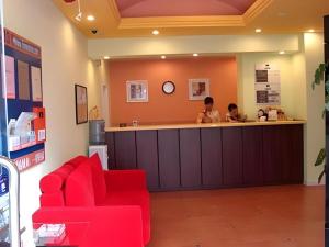a waiting room with a red couch and a counter at Home Inn Kunming Baita Road in Kunming