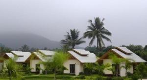 a white house with palm trees in front of it at Pangsarapee Resort in Ban Bo Nam Khao