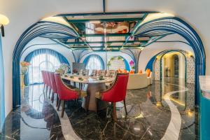 Nha Trang Prince Hotel في نها ترانغ: غرفة طعام مع طاولة طويلة وكراسي حمراء