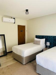 a bedroom with two beds and a mirror and a door at Greenlake Guesthouse in Maseru