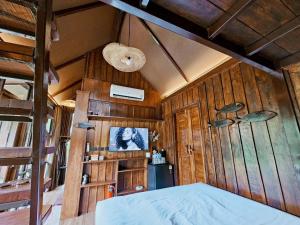 a bedroom with wooden walls and a bed in a room at Cheewatra Farmstay Coconut House in Ban Tha Maphrao