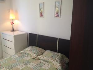 a bedroom with a bed and a dresser with a lamp at Apartamento Guarapari com aconchego in Guarapari