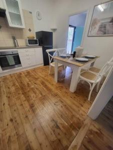 a kitchen with a table and chairs and a wooden floor at Family Friendly - 5 Mins To Beach in Belmont
