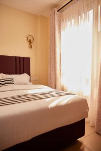 Lake View House- Shawmut Nakuru في ناكورو: غرفة نوم بها سرير ونافذة كبيرة +10 صور