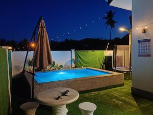 a swimming pool at night with a table and an umbrella at Homestay AGM in Mersing