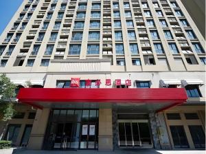 ibis Wuxi Jiangnan University في ووشي: مبنى كبير أمامه مظلة حمراء