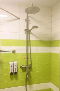 a shower in a green and white tiled bathroom at 7 Days Premium JiNan Jingshi Road Qilu Children's Hospital Exhibition Center in Jinan
