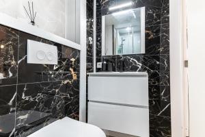 ヘントにある3 Stylish Studios at a Great Location in Gentの黒大理石の壁のバスルーム、白い冷蔵庫が備わります。