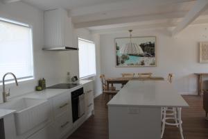 a white kitchen with a sink and a table at Beach Bound-Jervis Bay in Vincentia