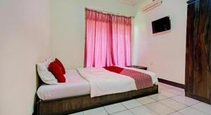 a bedroom with a bed with red pillows and a window at Hotel O Fj Guest House in Sayang
