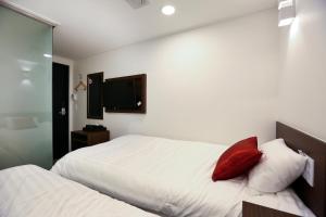 a bedroom with two beds and a red pillow at Tripstay Myeongdong in Seoul