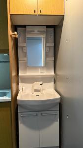 um banheiro com pia e espelho em Moon Base Tokyo Inn em Tóquio