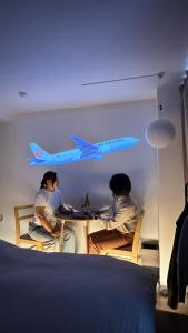 Tres personas sentadas en una mesa con un avión en la pared. en Moon Base Tokyo Inn, en Tokio