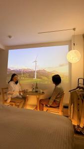 duas mulheres sentadas à mesa em uma sala com um moinho de vento em Moon Base Tokyo Inn em Tóquio
