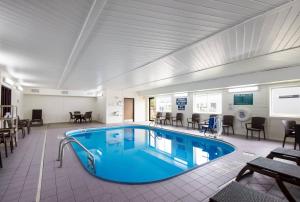 a pool in a room with tables and chairs at Quality Inn & Suites Green Bay - Ashwaubenon in Green Bay