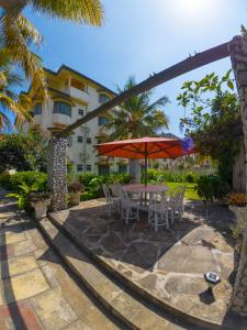a patio with a table and chairs and an umbrella at Cosy 1 BR with Swimming Pool & Garden & 25 Mins to Airport - C04 in Mombasa