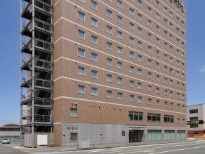 a tall red brick building with scaffolding on it at Comfort Hotel Kokura in Kitakyushu
