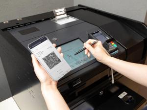 a person holding a cell phone in front of a cash register at Comfort Hotel Hamamatsu in Hamamatsu