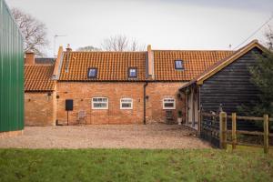 a brick building with a gate and a barn at Stunning 5-bed Barn Conversion in Newark-on-Trent by Renzo, Beautiful Surroundings, Sleeps 10! in Besthorpe