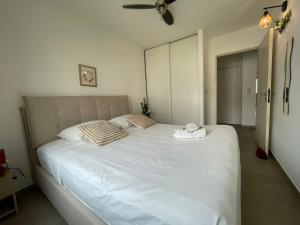 a bedroom with a large white bed with a ceiling fan at T3 Rosa - 59m2 avec piscine commune - Saint-Leu in Saint-Leu