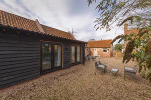 a backyard with two chairs and a house at Stunning 5-bed Barn Conversion in Newark-on-Trent by Renzo, Beautiful Surroundings, Sleeps 10! in Besthorpe