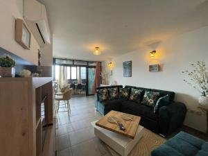a living room with a couch and a table at T3 Rosa - 59m2 avec piscine commune - Saint-Leu in Saint-Leu