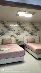 two beds in a room with a wall mural at Alanta aonang resort in Ban Khlong Haeng
