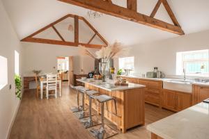 a kitchen with wooden cabinets and a kitchen island with bar stools at Stunning 5-bed Barn Conversion in Newark-on-Trent by Renzo, Beautiful Surroundings, Sleeps 10! in Besthorpe