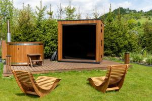a wooden deck with two chairs and a large screen at Zacisze Beskidu - Private House with Sauna, Jacuzzi & Pool in Łącko