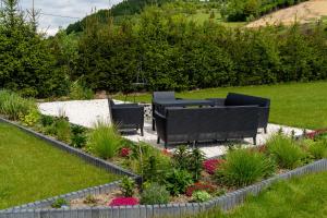 a garden with two black chairs and flowers at Zacisze Beskidu - Private House with Sauna, Jacuzzi & Pool in Łącko +37 photos
