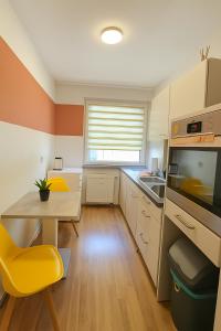 a small kitchen with a table and a yellow chair at Moderne 3-Zimmer-Ferienwohnung in Emersleben in Halberstadt +3 photos