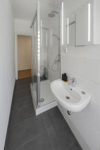 a white bathroom with a shower and a sink at Moderne 3-Zimmer-Ferienwohnung in Emersleben in Halberstadt
