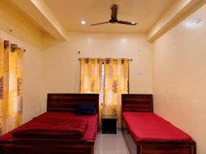 1 Schlafzimmer mit 2 Betten mit roter Bettwäsche und einem Fenster in der Unterkunft Studio 304 Modern Serenity in Deoghar
