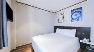 a bedroom with a white bed and some pictures on the wall at Sun Land Hotel Jeju in Jeju