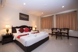 a bedroom with a large bed and a table and chairs at True Siam Rangnam Hotel in Bangkok