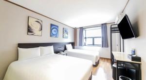 a hotel room with a bed and a tv at Sun Land Hotel Jeju in Jeju