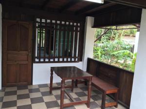 a table and bench in a room with a window at Hora Home in Lampang