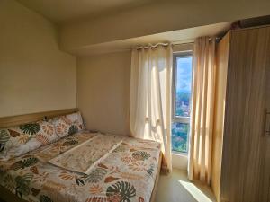 a bedroom with a bed and a large window at Avida Abreeza 1bedroom with balcony in Davao City +12 photos
