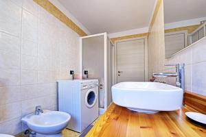 y baño con bañera, lavabo y lavadora. en Maison Henri, en Morgex