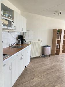 a kitchen with white cabinets and a wooden floor at Residenz Polderblick Burgerbrug in Burgerbrug