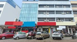 Hotel O M&h Hotel في Kampung Sungai Rengit: مجموعة من السيارات متوقفة أمام مبنى