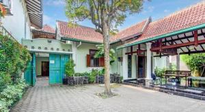 Capital O 93938 Wisma Pamungkas Syariah في Ngemplak: منزل بأبواب زرقاء وشجرة في الفناء